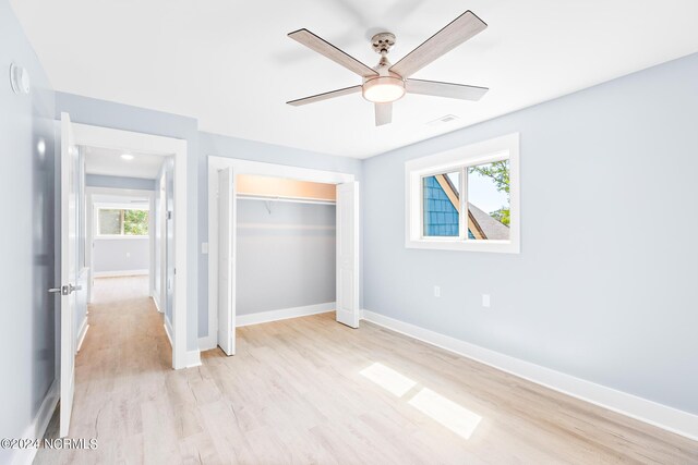 31 Augusta Dr, Oak Island, NC 28465 - unfurnished bedroom with light wood finished floors, multiple windows, and a closet