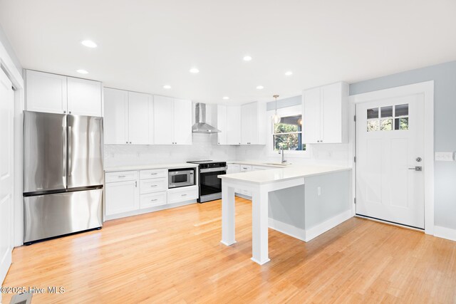 31 Augusta Dr, Oak Island, NC 28465 - kitchen with a peninsula, stainless steel appliances, wall chimney range hood, light countertops, and decorative backsplash
