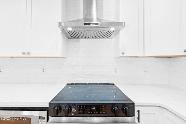31 Augusta Dr, Oak Island, NC 28465 - details featuring white cabinets, wall chimney range hood, decorative backsplash, and stainless steel electric stove