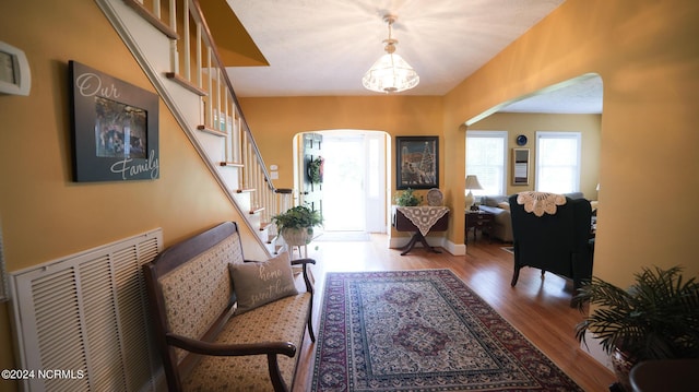 entryway featuring arched walkways, wood finished floors, visible vents, baseboards, and stairs