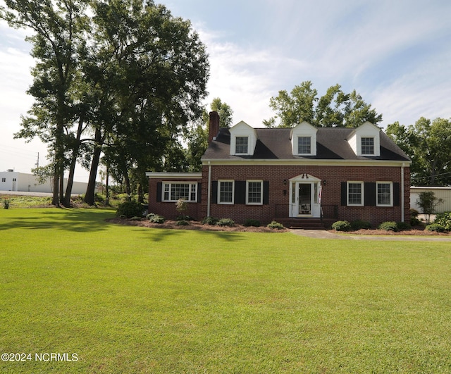 cape cod house featuring brick siding and a front yard