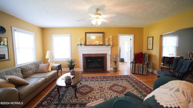 living area featuring plenty of natural light, a fireplace, arched walkways, and wood finished floors