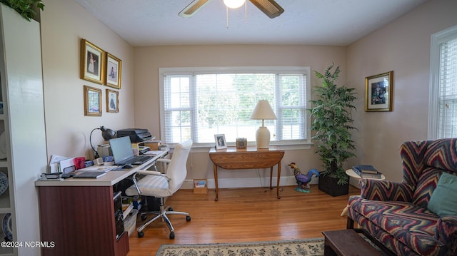 home office featuring a healthy amount of sunlight, baseboards, a ceiling fan, and wood finished floors