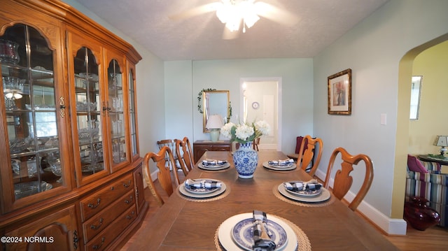 dining space featuring arched walkways, a textured ceiling, and baseboards