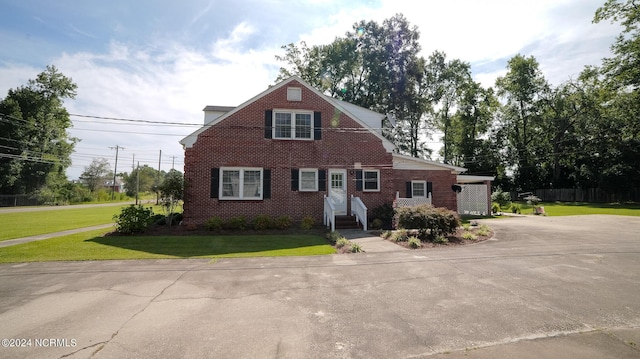 view of front of house featuring driveway, a front lawn, and brick siding