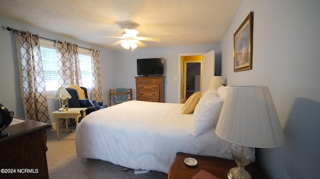 carpeted bedroom with ceiling fan and a textured ceiling