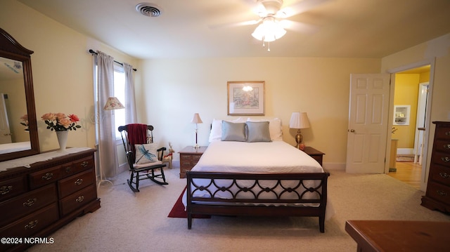 bedroom with light carpet, ceiling fan, visible vents, and baseboards