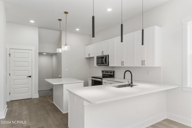 kitchen with hanging light fixtures, stainless steel appliances, kitchen peninsula, sink, and white cabinets