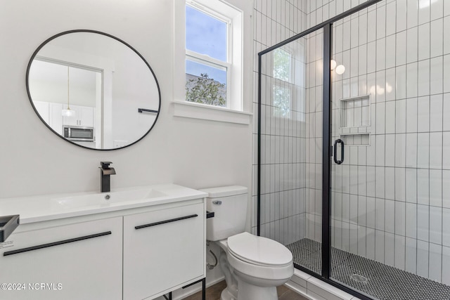 bathroom with a shower with door, vanity, and toilet