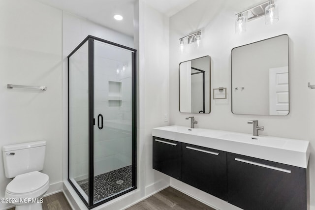 bathroom featuring toilet, hardwood / wood-style flooring, vanity, and a shower with door