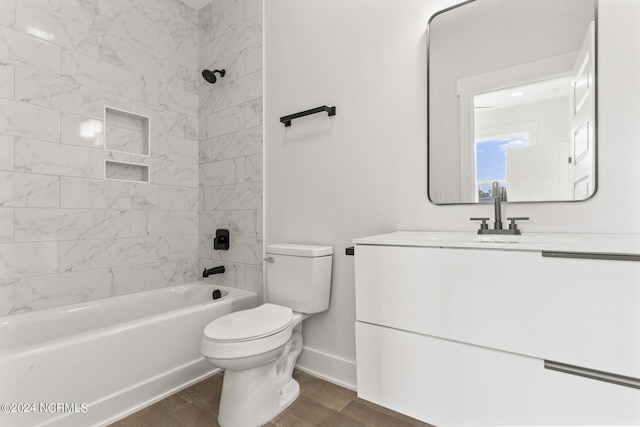 full bathroom featuring vanity, tiled shower / bath combo, hardwood / wood-style flooring, and toilet