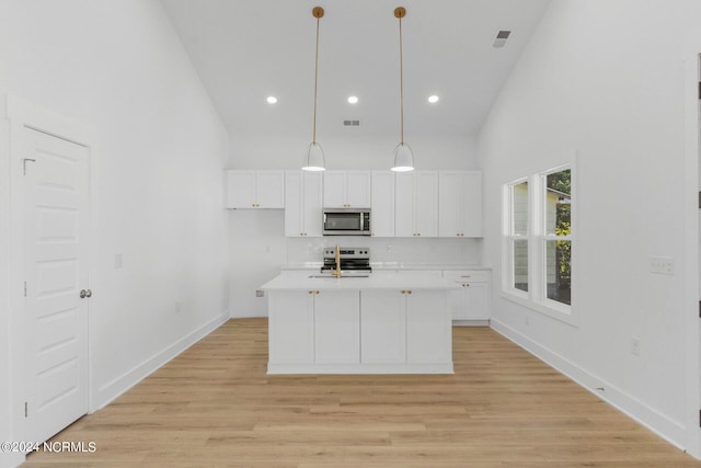 kitchen featuring appliances with stainless steel finishes, hanging light fixtures, white cabinets, light hardwood / wood-style flooring, and a center island with sink