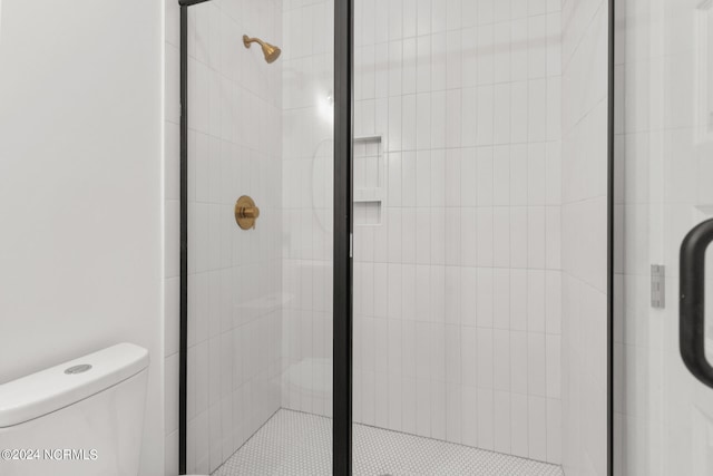 bathroom featuring a shower with door and toilet