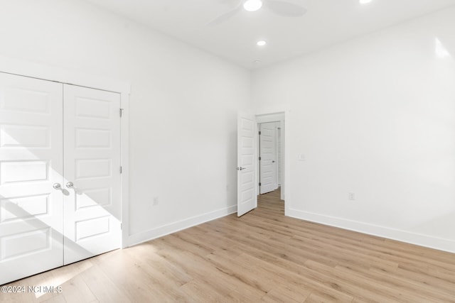 unfurnished bedroom featuring a closet, light hardwood / wood-style floors, and ceiling fan