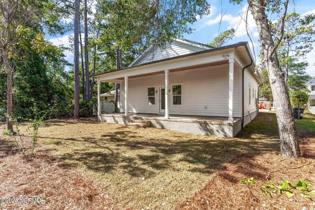 back of house featuring covered porch and a yard