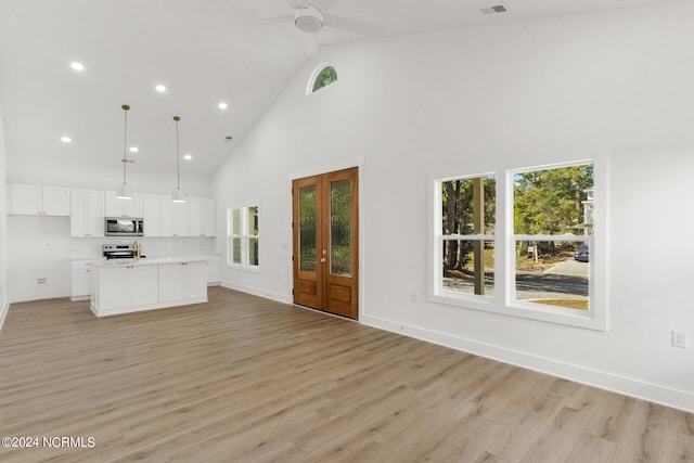 kitchen featuring white cabinetry, a kitchen island with sink, light hardwood / wood-style flooring, pendant lighting, and stainless steel appliances