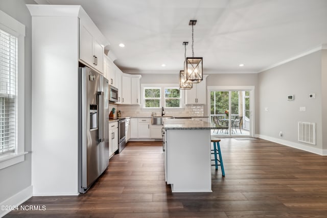 kitchen with appliances with stainless steel finishes, a kitchen island, a breakfast bar area, and dark wood-type flooring