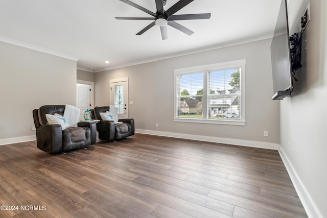 sitting room with ceiling fan, ornamental molding, and dark wood-type flooring