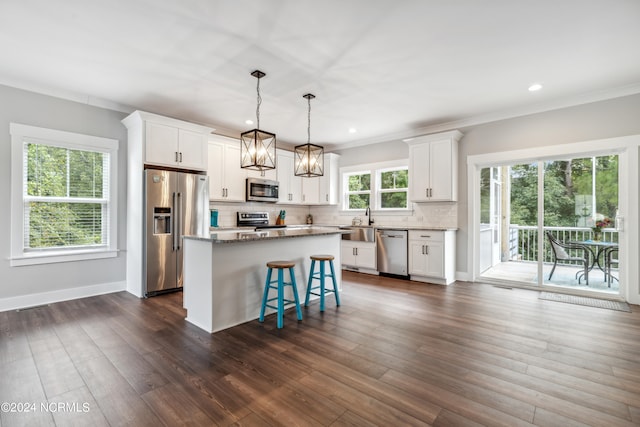 kitchen with white cabinets, appliances with stainless steel finishes, dark wood-type flooring, and a kitchen island