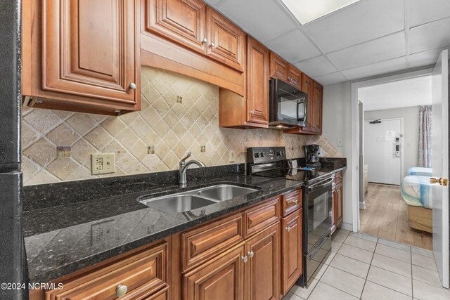 1501 S Ocean Blvd Unit 1235, Myrtle Beach, SC 29577 - kitchen featuring brown cabinets, light tile patterned floors, tasteful backsplash, a sink, and black appliances