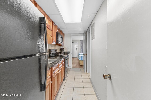 1501 S Ocean Blvd Unit 1235, Myrtle Beach, SC 29577 - kitchen featuring baseboards, brown cabinetry, a paneled ceiling, black appliances, and light tile patterned flooring