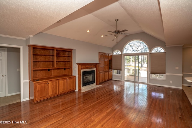 unfurnished living room with hardwood / wood-style flooring, a premium fireplace, vaulted ceiling, and a textured ceiling