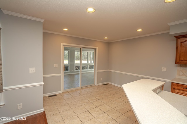 kitchen with a textured ceiling, backsplash, crown molding, and light tile patterned floors