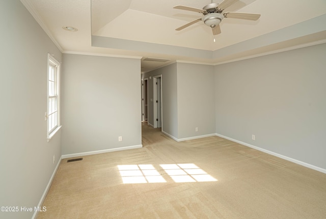 carpeted spare room with a raised ceiling, ceiling fan, and ornamental molding