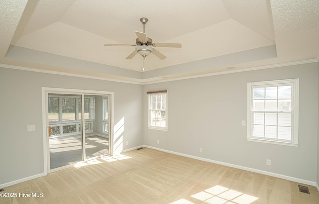 carpeted empty room with a raised ceiling, crown molding, and ceiling fan