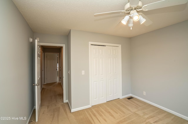 unfurnished bedroom with ceiling fan, a textured ceiling, light carpet, and a closet