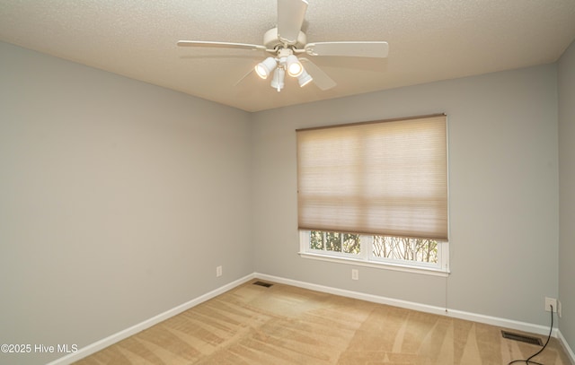 empty room featuring ceiling fan, light carpet, and a textured ceiling