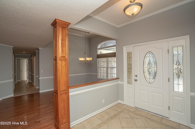 entrance foyer with ornamental molding, light hardwood / wood-style floors, an inviting chandelier, and a textured ceiling