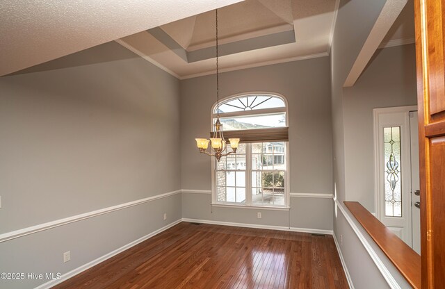 empty room with hardwood / wood-style floors, a notable chandelier, and ornamental molding