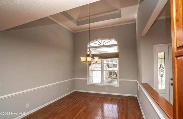 interior space with dark hardwood / wood-style flooring, a raised ceiling, an inviting chandelier, and crown molding