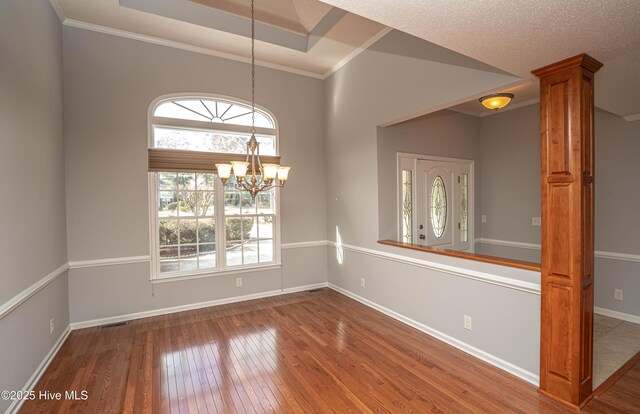 empty room with crown molding, hardwood / wood-style flooring, a chandelier, and a healthy amount of sunlight