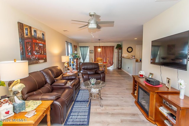 living room featuring visible vents, baseboards, a ceiling fan, and light wood-style floors