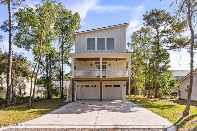 view of front of property with covered porch, a garage, a front lawn, and ceiling fan