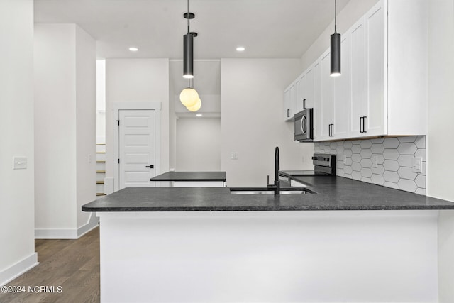 kitchen featuring appliances with stainless steel finishes, kitchen peninsula, decorative light fixtures, and white cabinetry