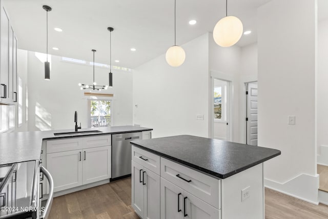 kitchen with dark countertops, a sink, electric range oven, light wood-style flooring, and stainless steel dishwasher