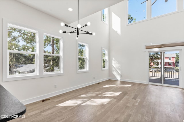 unfurnished living room with a chandelier, a healthy amount of sunlight, and wood finished floors
