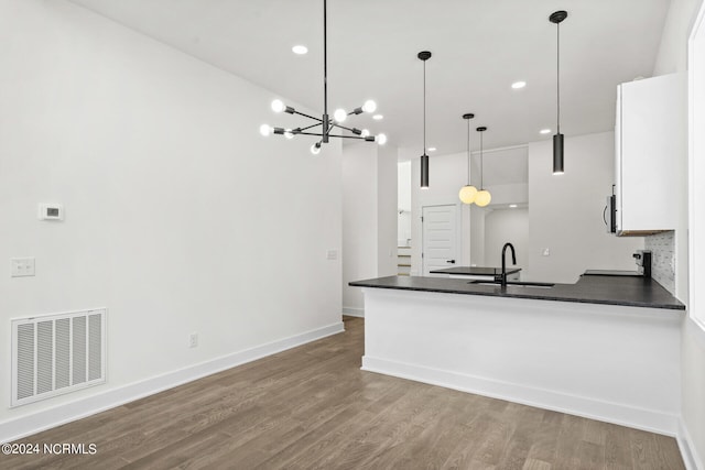 kitchen with white cabinetry, sink, pendant lighting, and hardwood / wood-style floors