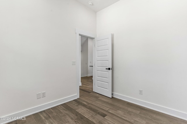 spare room featuring baseboards and dark wood-style flooring