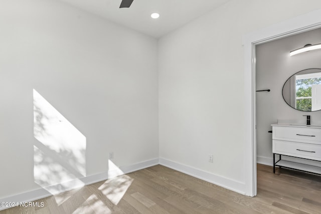 unfurnished bedroom featuring light wood-style floors, a sink, baseboards, and recessed lighting