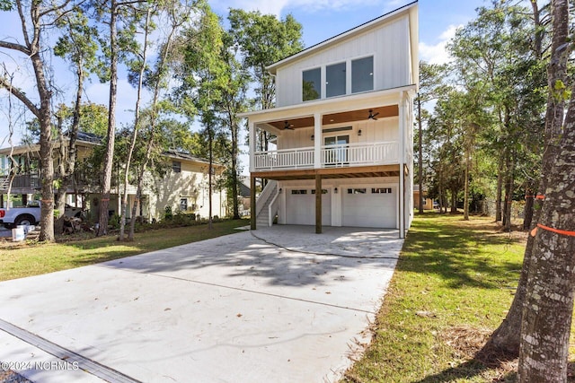 view of front of house featuring a front lawn, ceiling fan, board and batten siding, driveway, and stairway