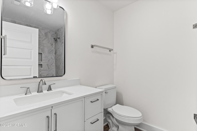 bathroom featuring vanity, walk in shower, and toilet