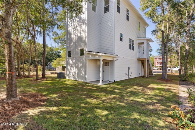 back of property featuring a lawn, cooling unit, and stairway