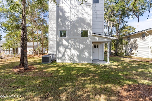 rear view of property featuring a yard and cooling unit