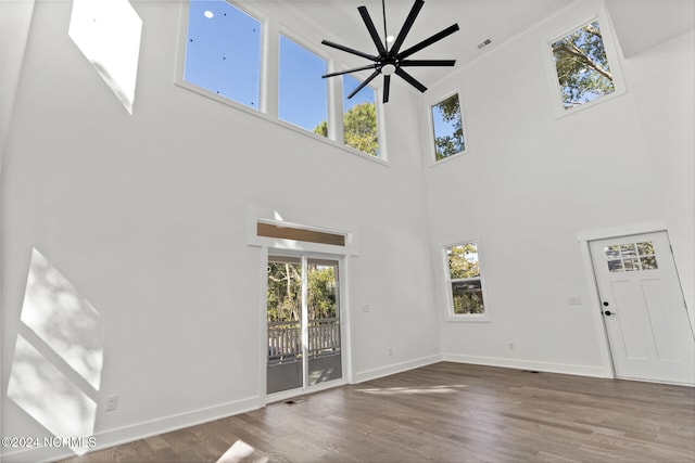 unfurnished living room with hardwood / wood-style flooring, a high ceiling, and ceiling fan