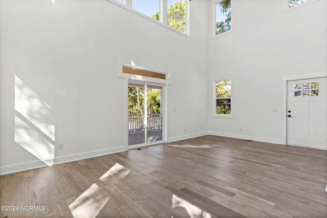 unfurnished living room featuring plenty of natural light, wood finished floors, and a high ceiling
