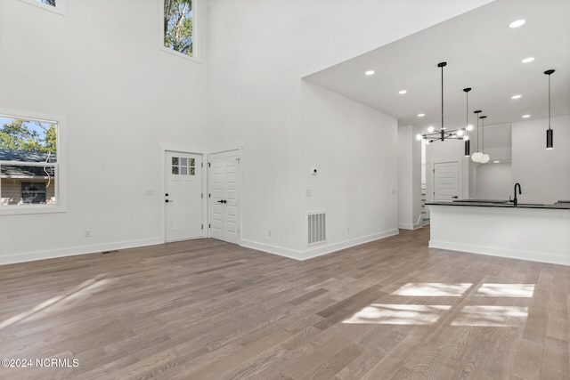 unfurnished living room featuring baseboards, visible vents, a sink, and light wood-type flooring